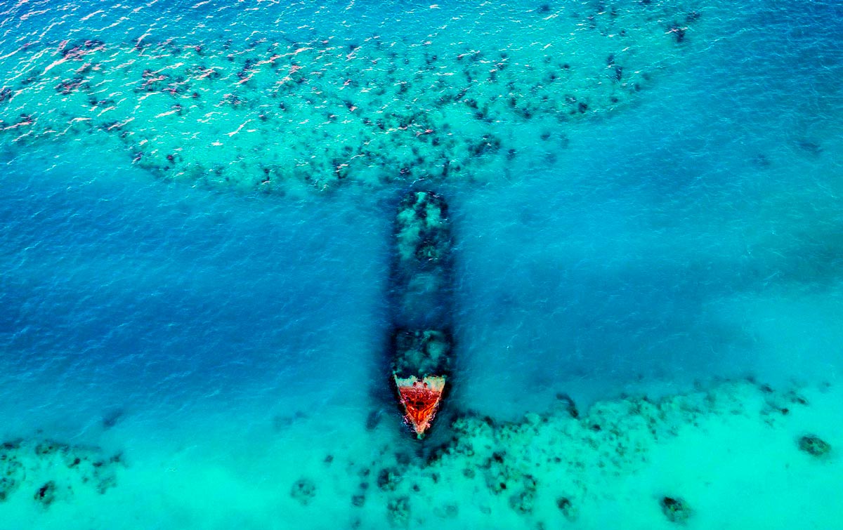 Поиск сокровищ — это захватывающая, но рутинная и тяжелая работа. Авиаразведка перемежается с бесчисленными погружениями в незнакомых водах, и лишь изредка, мелькает золотой лучик находки. Современное затонувшее судно на Багамских островах — вид с воздуха.
